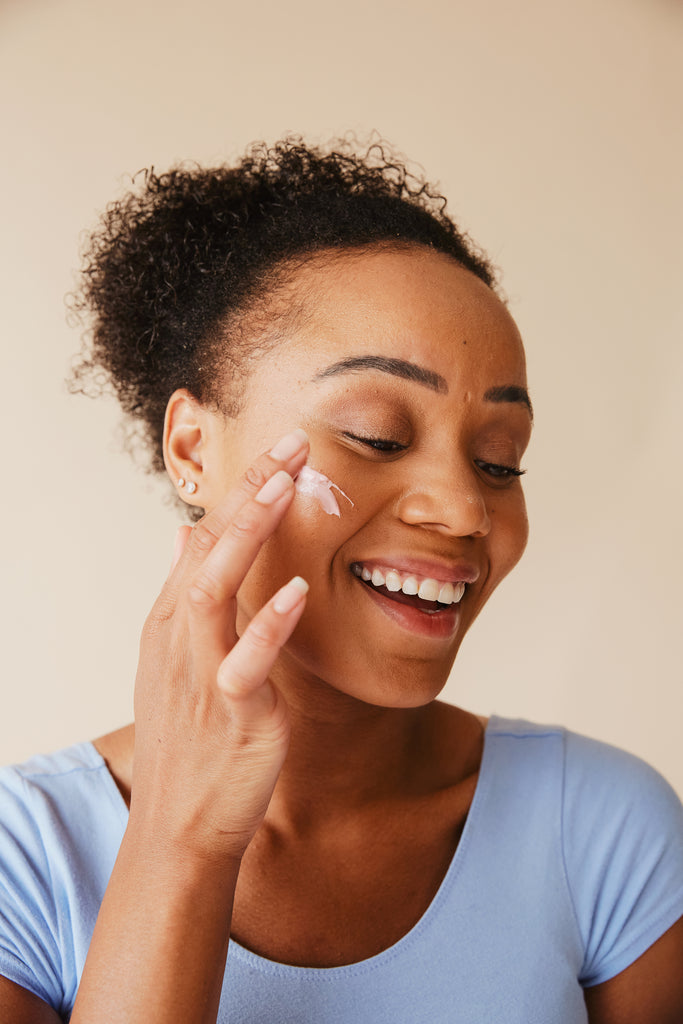 a girl putting cream in her face with smile