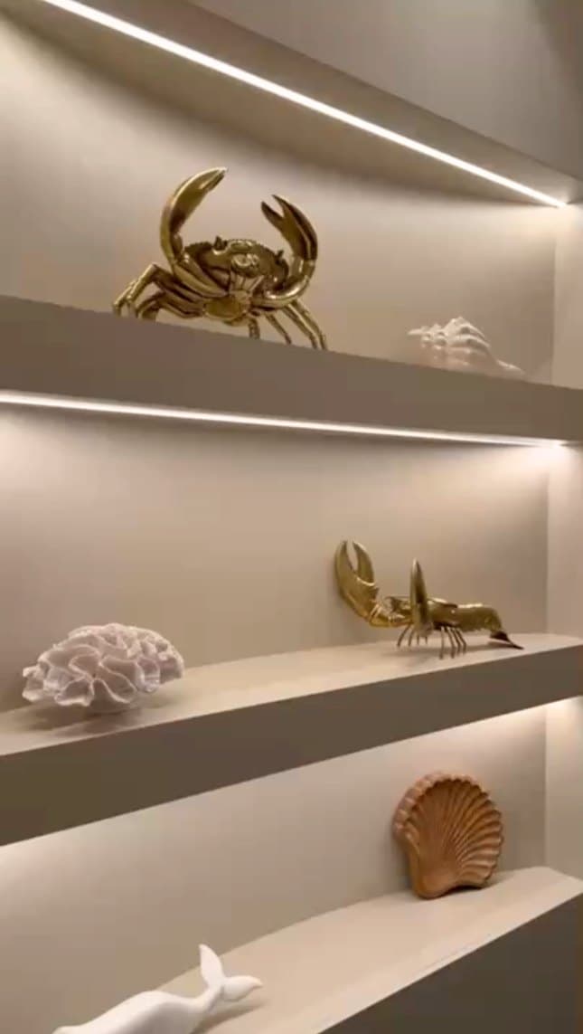 Gold crab sculptures and shells on lit lounge shelves