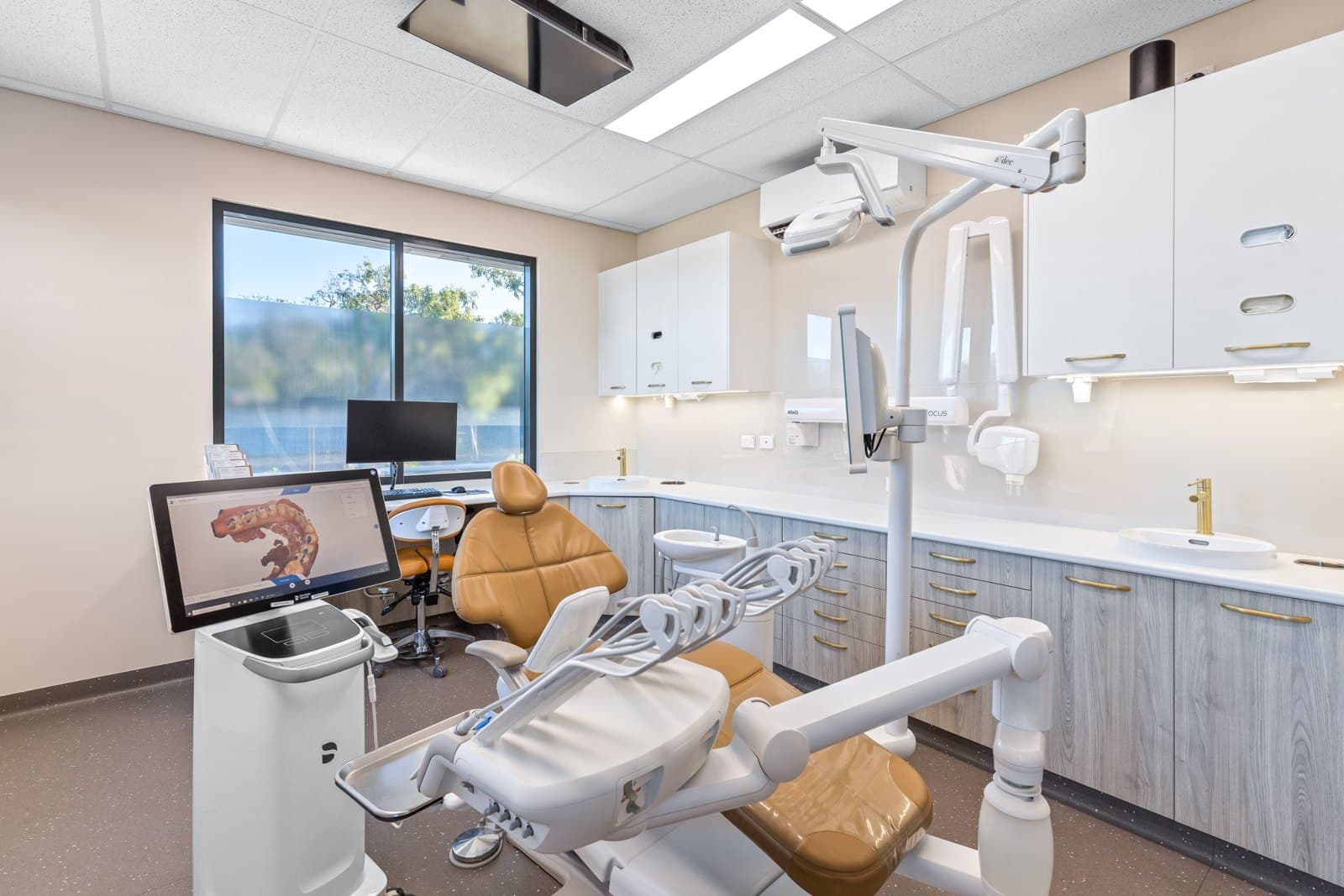 A calm surgery with natural light, a ceiling TV and clear benches