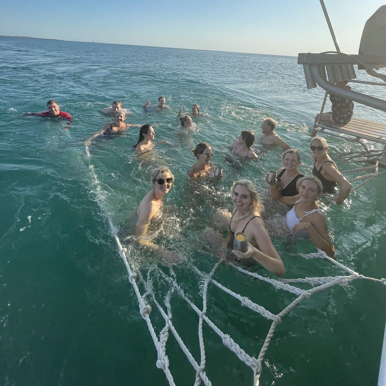 Friends swimming off the back of a boat