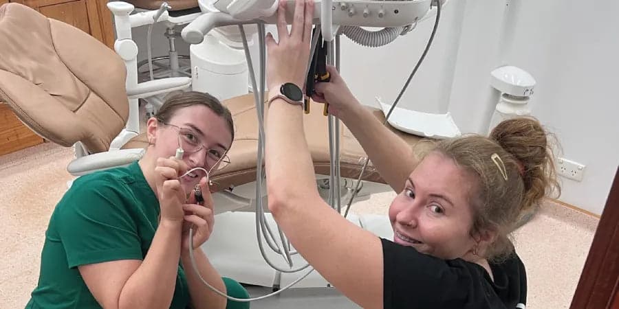 Two dental team members posing beside dental equipment