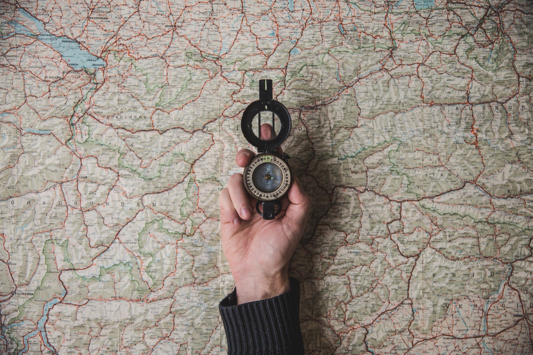 Hand holding a compass above a map