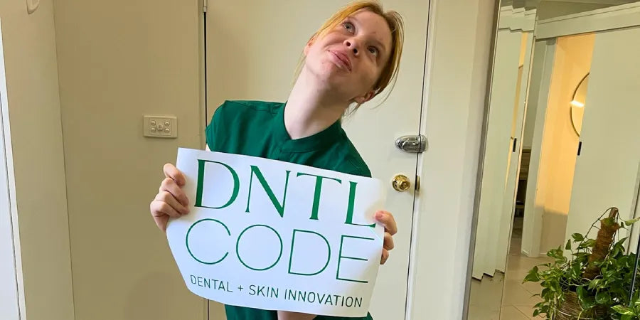 Team member in scrubs holding a DNTL Code sign