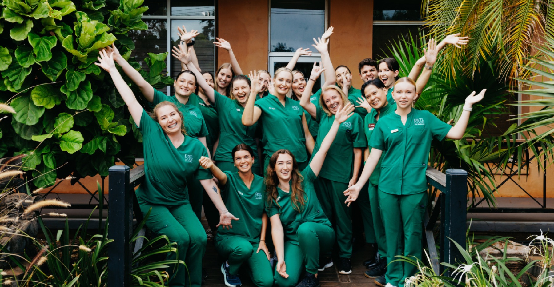 DNTL Code team in green scrubs posing outside the clinic