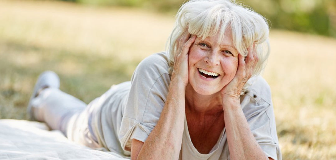 Smiling older woman lying on grass