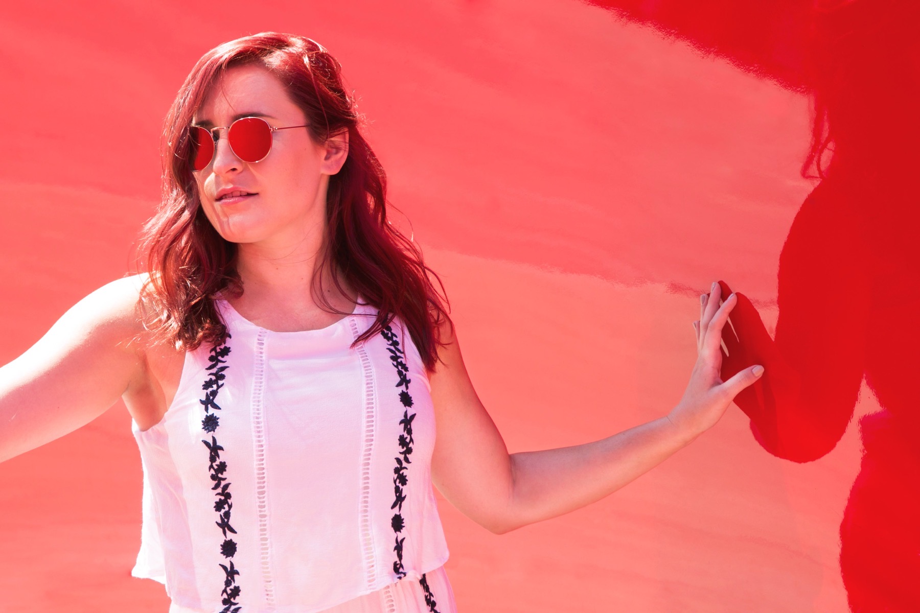 Woman in sunglasses against a red wall