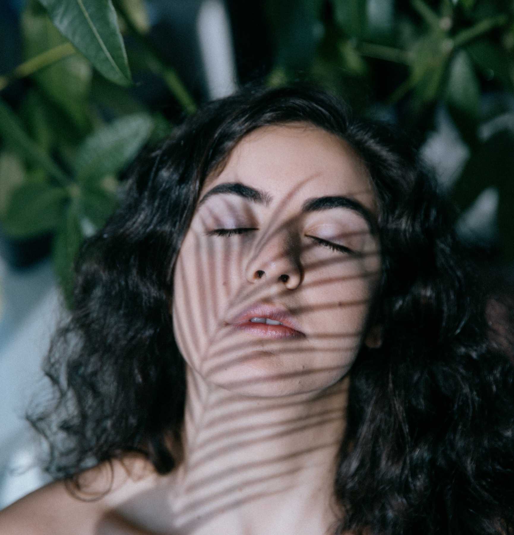 Woman with eyes closed and leaf shadows across her face